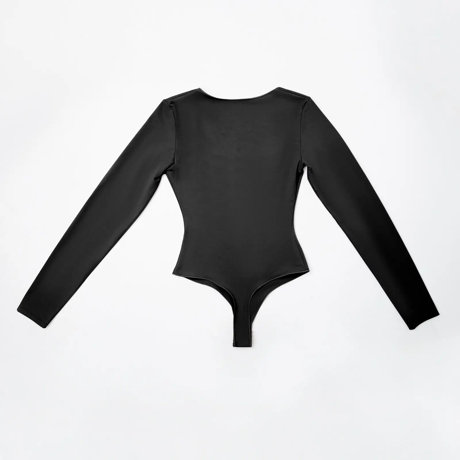 A black long sleeve low cut bodysuit lying with front faced down over a white background