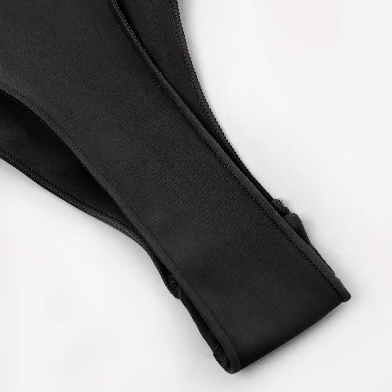 Close-up of black snap-on thong over a white background.