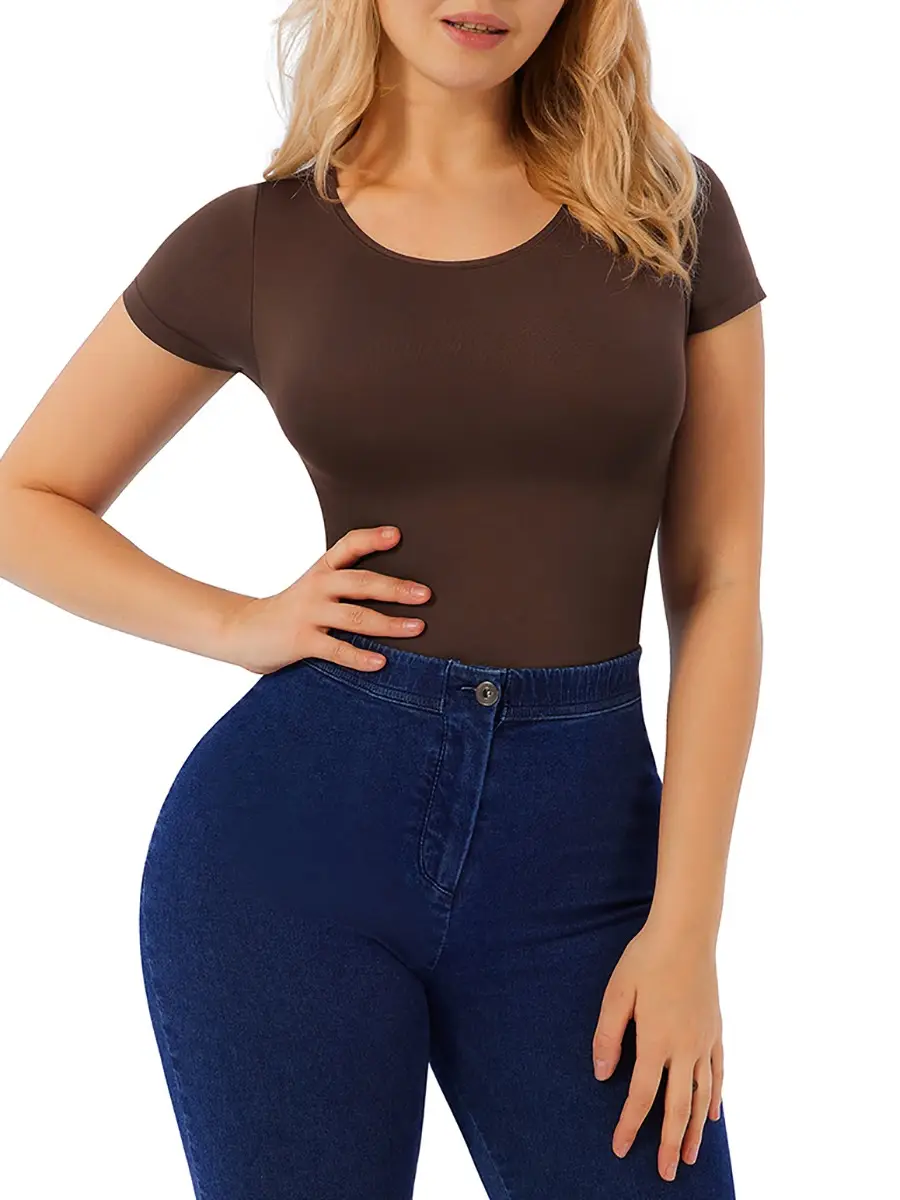 Caucasian blonde woman posing with hand on hip wearing a brown t-shirt bodysuit with blue jeans over a white background